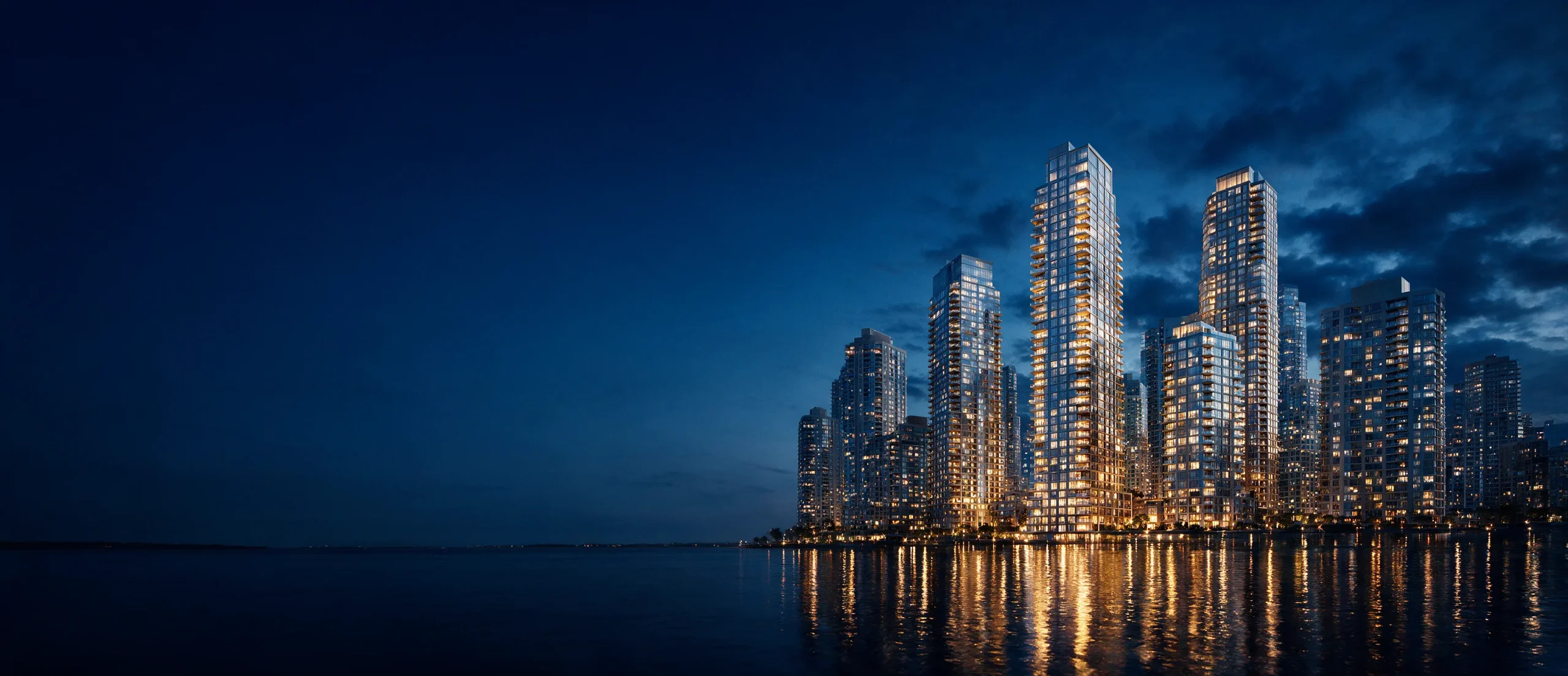 Illuminated waterfront residential towers at dusk, their lights reflected in calm water